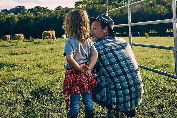 © iStock.com/pixdeluxe Vater und Tochter beobachten Kühe auf einer Weide