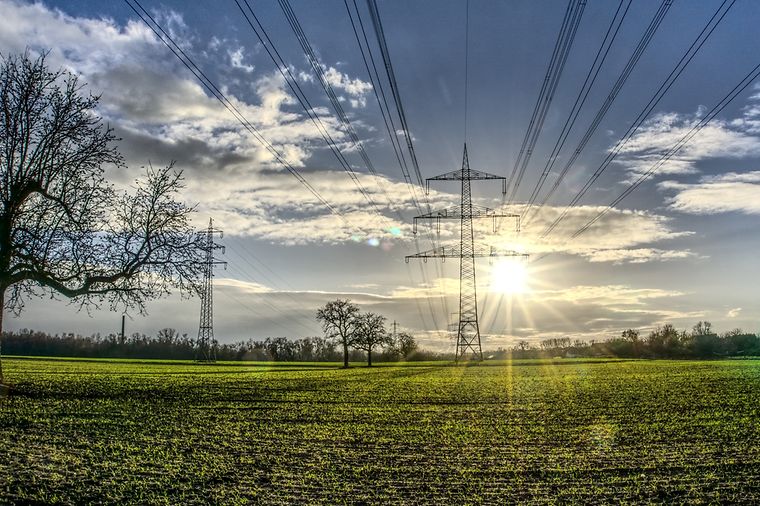 © Mainova Freileitungsmasten auf einem Feld, Sonne strahlt am Himmel