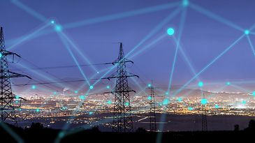 © stock.adobe.com/urbans78 Vernetzte Strommasten vor einer Großstadt