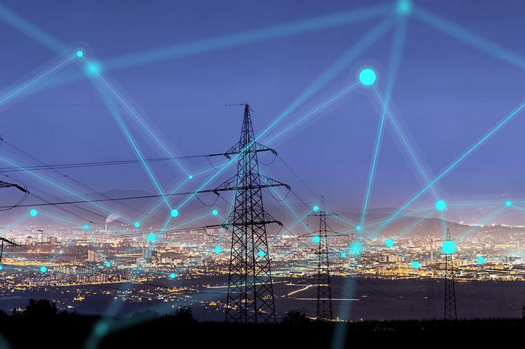 © stock.adobe.com/urbans78 Vernetzte Strommasten vor einer Großstadt