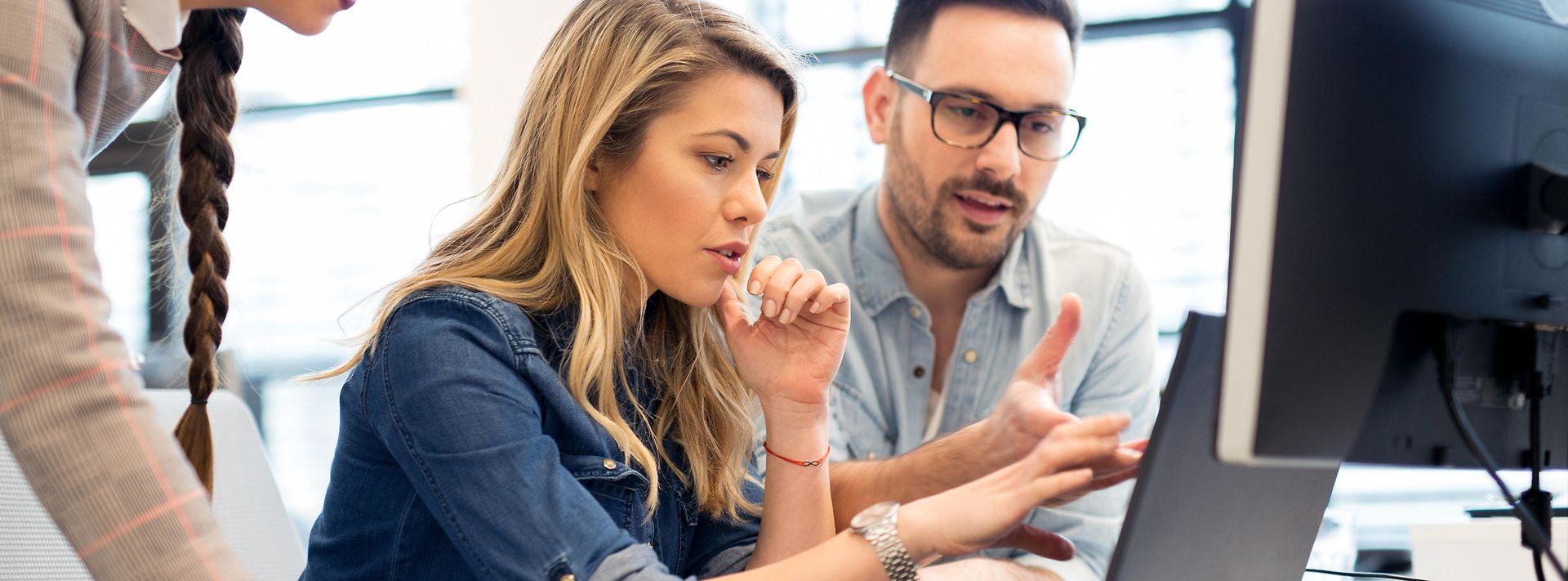 Mann und Frau im Büro schauen gemeinsam auf Laptop und besprechen sich