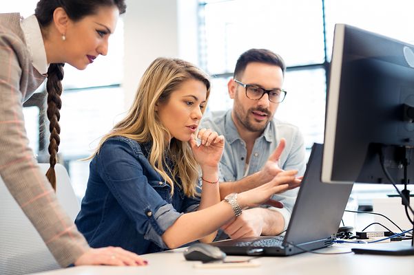 Mann und Frau im Büro schauen gemeinsam auf Laptop und besprechen sich