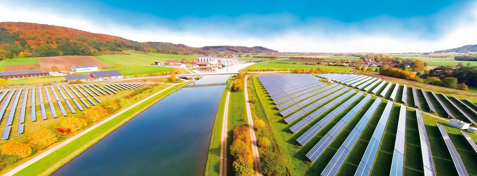 Grüne Felder mit Fluss und Photovoltaikanlagen aus der Vogelperspektive