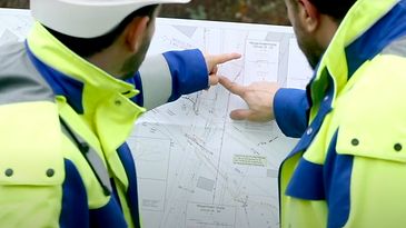 © Mainova Ingenieure stehen vor einer Zeichnung und deuten mit den Fingern darauf