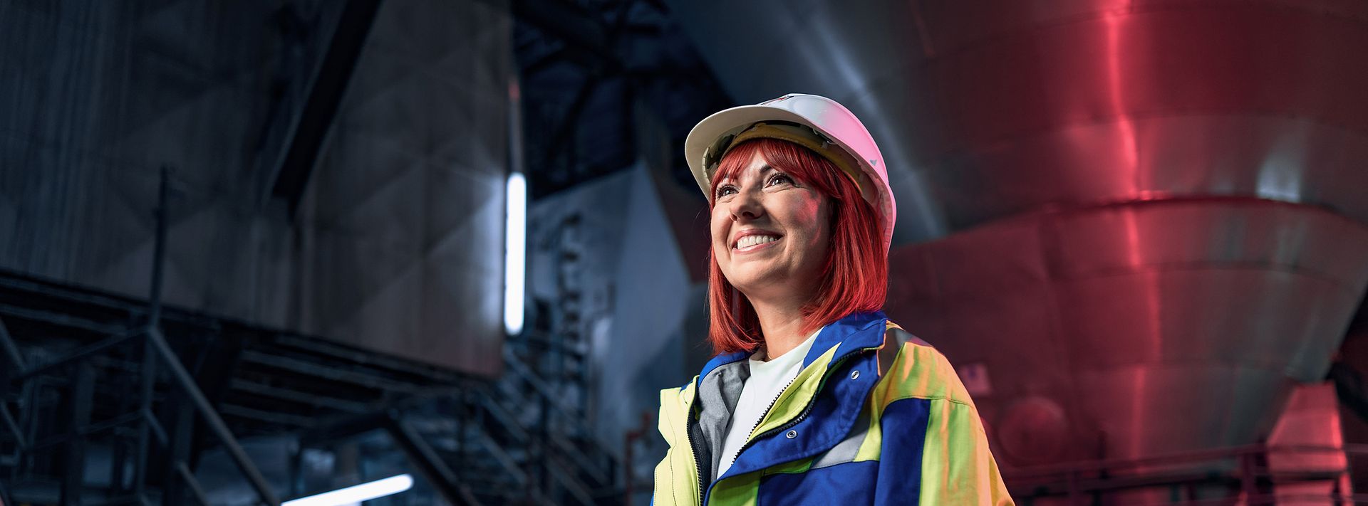 Junge Frau mit Helm und Warnweste auf Baustelle