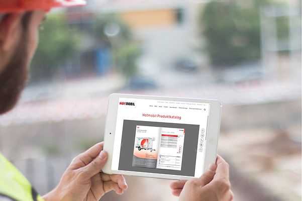 Ein Mann schaut auf das Display seines Tablets, das Onlinekatalog zeigt