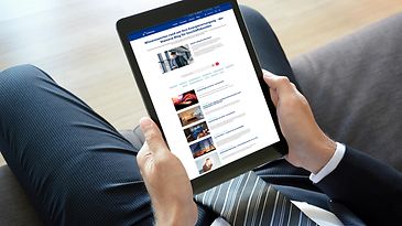 Eine Person im Anzug hält ein Tablet, auf dem der Mainova Blog für Geschäftskunden geöffnet ist.