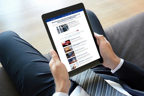 Eine Person im Anzug hält ein Tablet, auf dem der Mainova Blog für Geschäftskunden geöffnet ist.