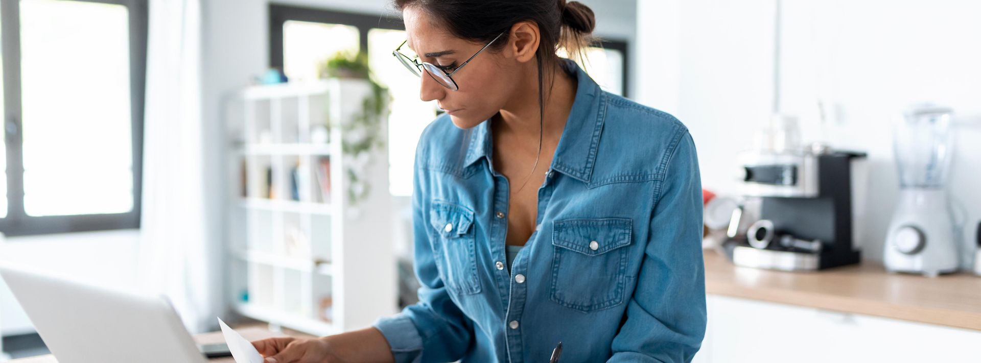 © stock.adobe.com/nenetus Junge Frau sitzt zu Hause vor ihrem Laptop und füllt einen Antrag aus.