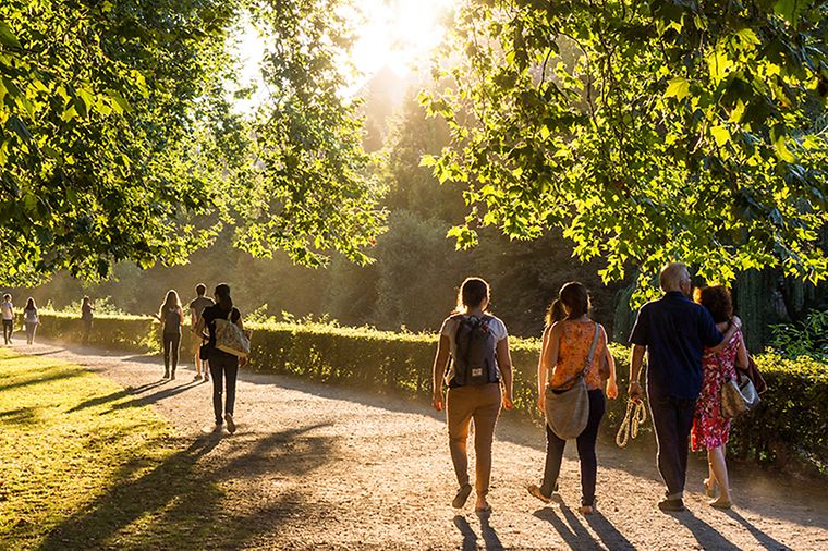 Menschen gehen in einem Park spazieren, die Sonne scheint