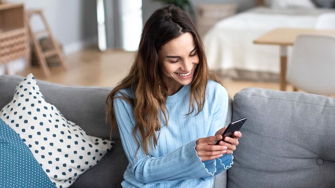 Frau sitzt mit Smartphone auf dem Sofa