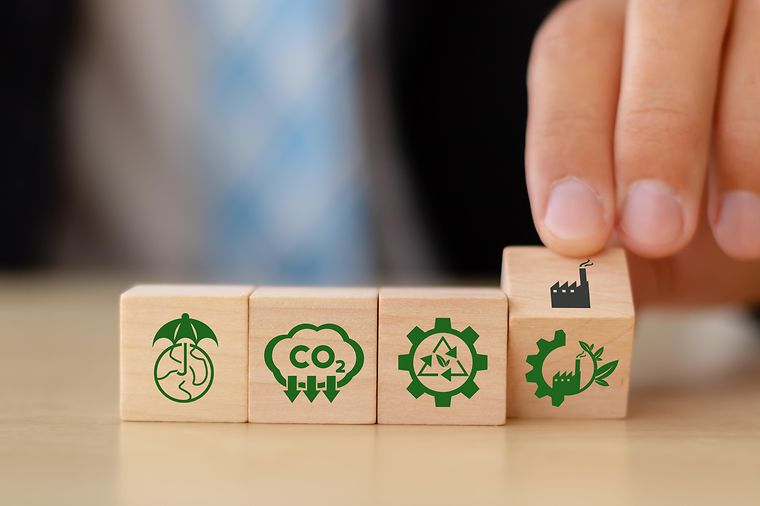 Vier Holzwürfel mit Symbolen für Klimaneutralität