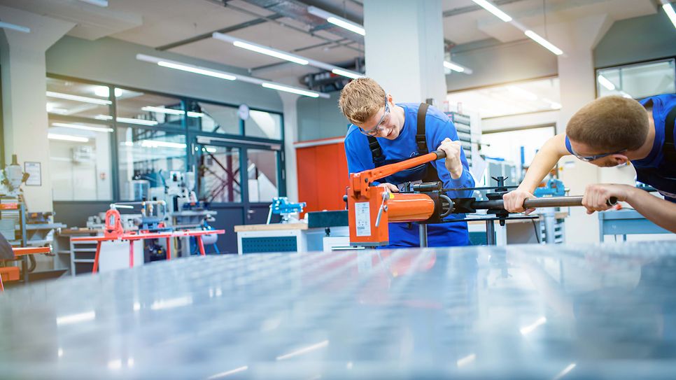 Auszubildende stehen an einer Presse und bedienen sie
