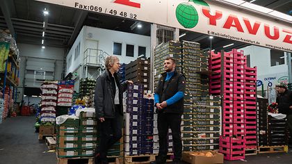 Frau und Mann unterhalten sich im Lager vor Vorratskisten