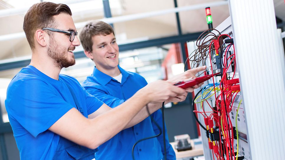 Zwei auszubildende prüfen am Schaltschrank mit einen Prüfgerät