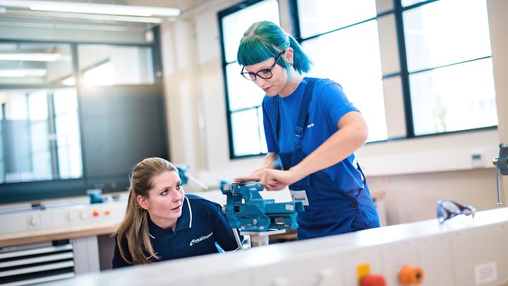 © Mainova/AndreFormer Ausbilderin kontrolliert die Arbeit einer Auszubildenden an einen Schraubstock