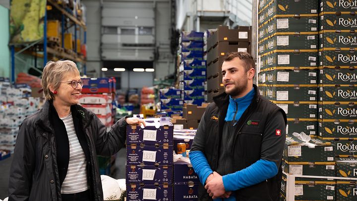 Dame mit kurzen grauen Haaren unterhält sich freundlich mit einem Lagermitarbeiter
