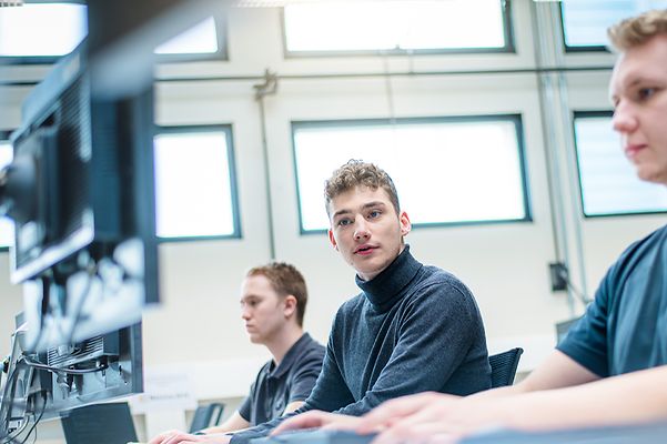 © Mainova/AndreFormer Auszubildende sitzen alle am Computer und ein Auszubildender schaut auf dem Monitor des anderen