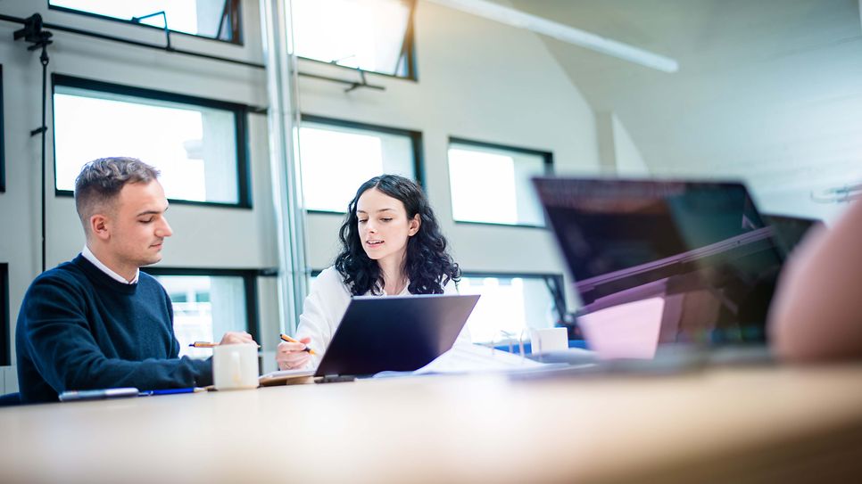 Auszubildene erklärt Kollegen am Notebook etwas