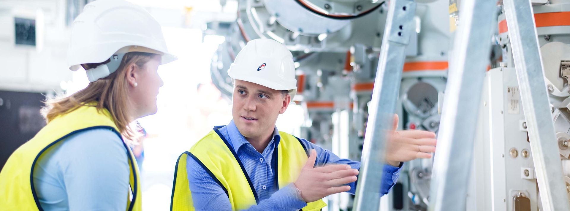 Ausbilder erklärt einer Auszubildenden eine Maschine