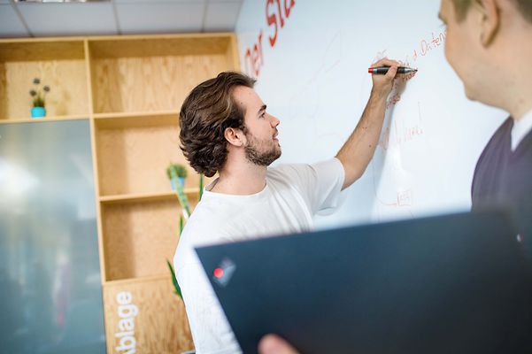 Auszubildender schreibt ein Text auf das Flipchart