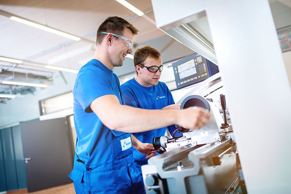 Zwei Auszubildende stehen an Drehmaschine