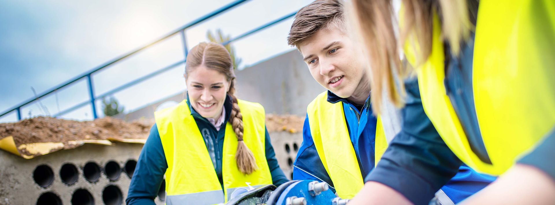 Gruppe Studenten sitzen auf einer Baustelle und betrachten einen Bauplan