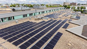 Auf einem Flachdach sind zahlreiche Solarpaneele installiert, die Sonnenenergie in Strom umwandeln.