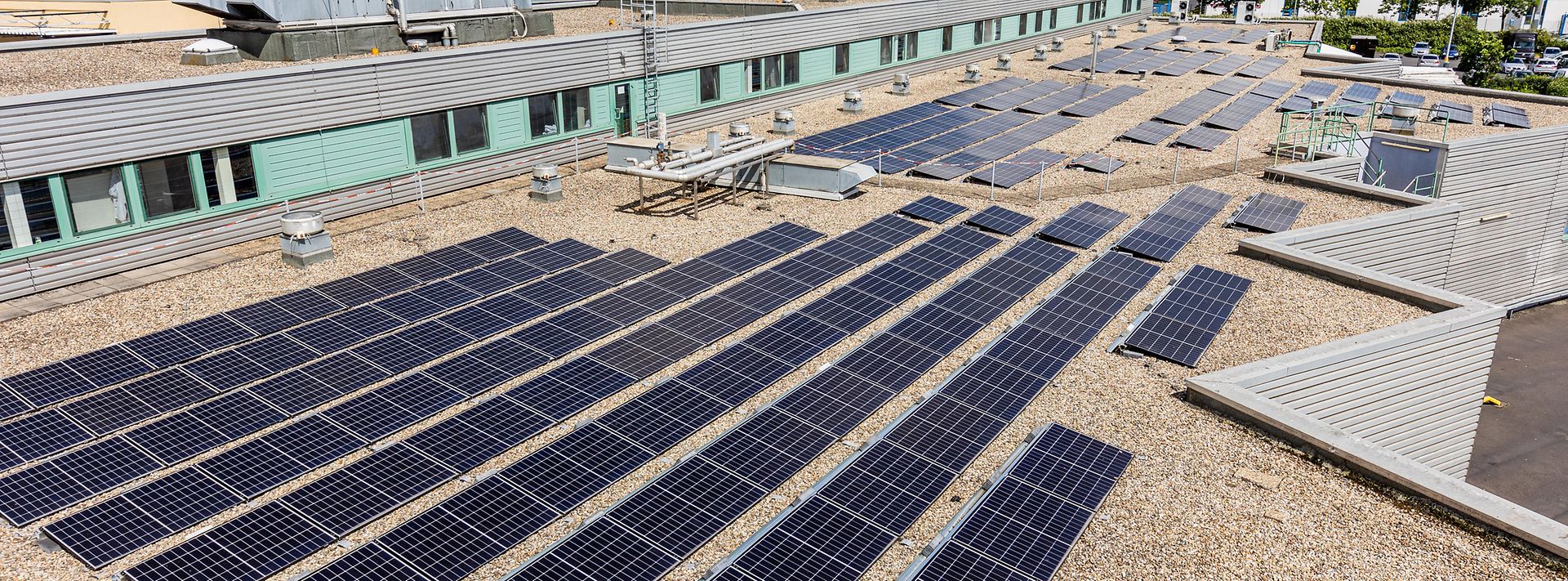 Auf einem Flachdach sind zahlreiche Solarpaneele installiert, die Sonnenenergie in Strom umwandeln.